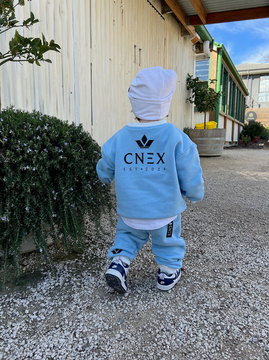 Child wearing a blue outfit with 'CNEX' branding outdoors.