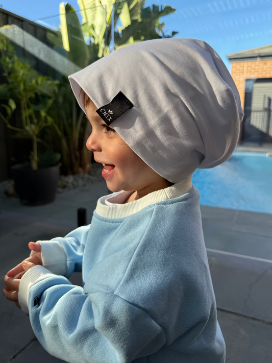 Child wearing a gray hoodie with a brand tag outdoors
